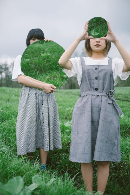 Two Girls Holding Round Mirrors
