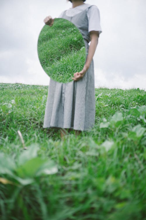Woman in Gray Dress Standing on Green Grass Field