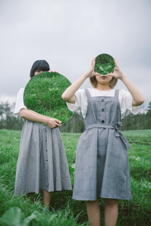 Two Women Holding Round Mirrors
