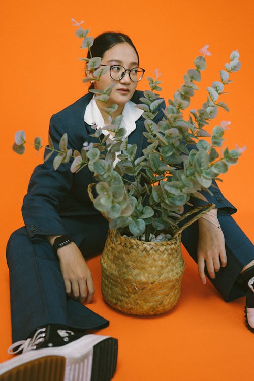 Woman in Black Framed Eyeglasses Sitting Near Green Plants