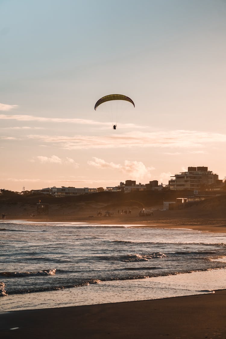 Silhouette Of Person Paragliding Over Ocean