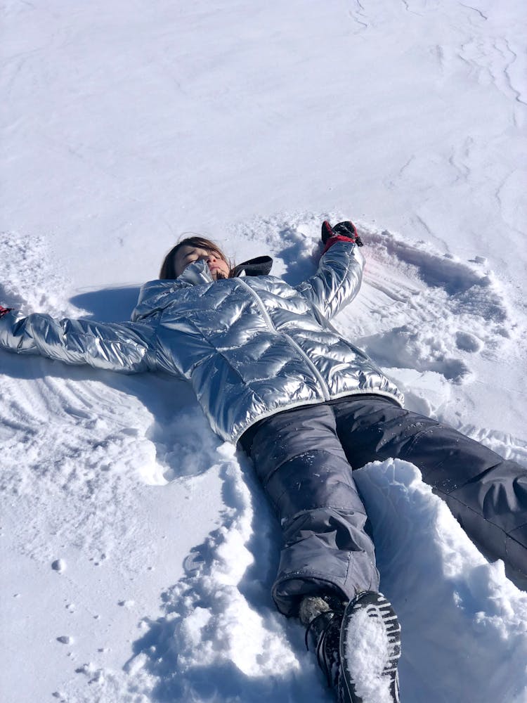 A Woman In Winter Clothing Making A Snow Angel