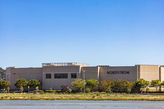 A Nordstrom store building set against a bright clear sky and surrounded by greenery.