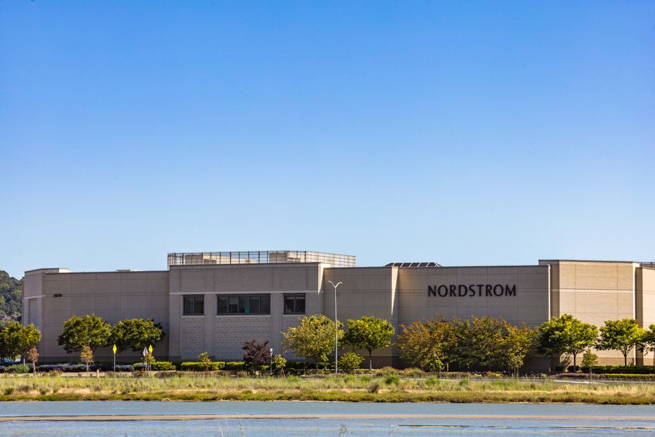 Photo by Robert So A Nordstrom store building set against a bright clear sky and surrounded by greenery.