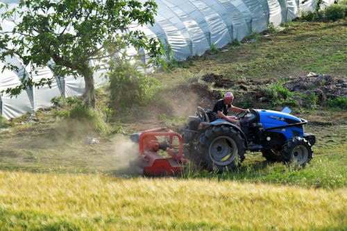 Man Driving Blue Tractor on Green Grass Field