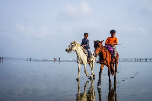 Free Two boys horseback riding on the beach, enjoying the sunny day. Stock Photo