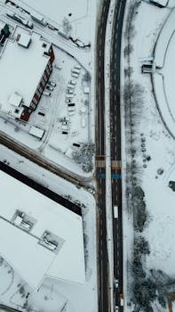 A top-down winter view of snow-covered roads and buildings in Yalova, Turkey, captured from above.