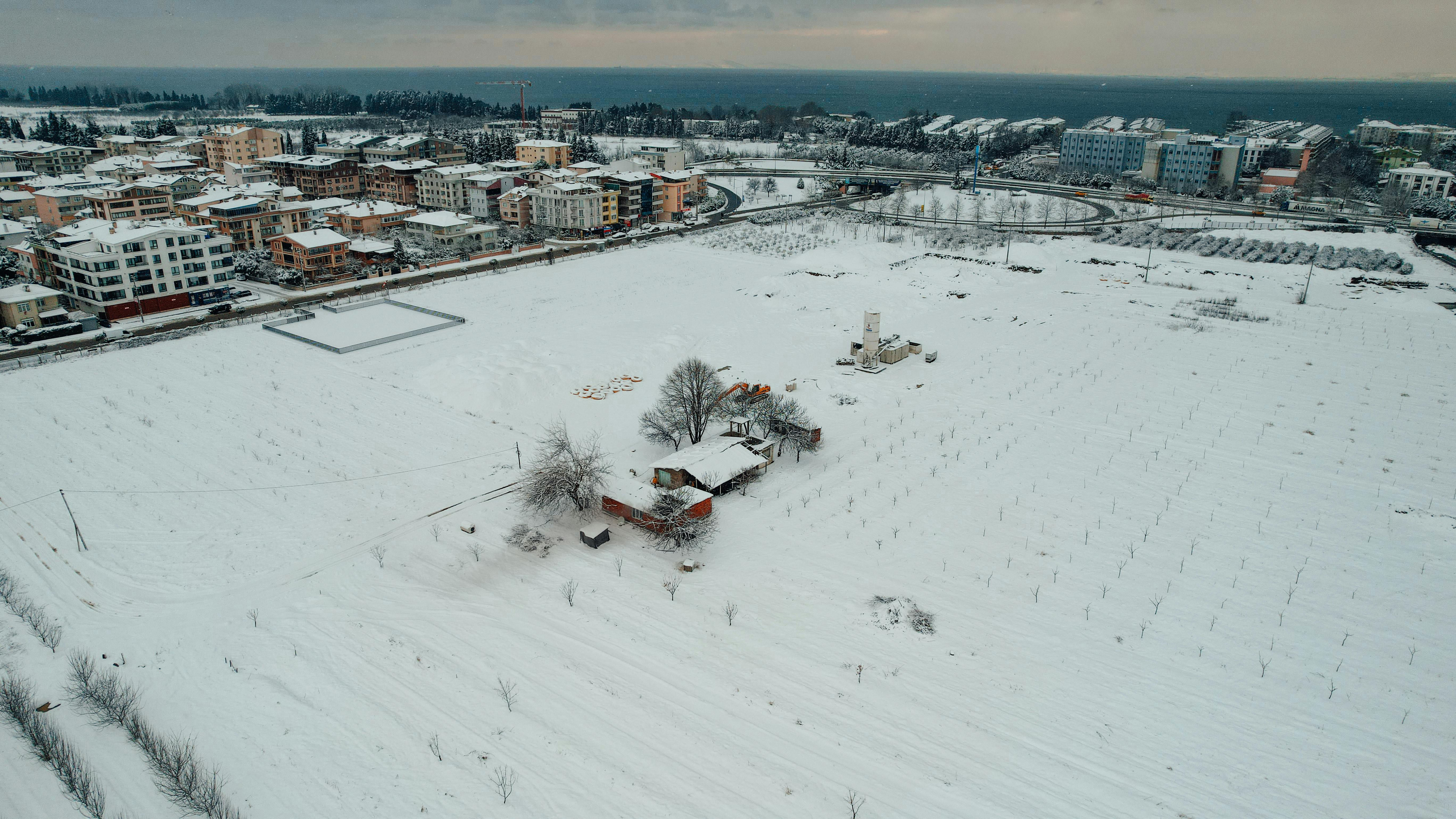 Aerial view of snow-covered fields and buildings in Yalova, Turkey during winter.