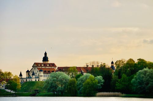 Free Scenic view of Niasviž Castle surrounded by lush greenery during sunset in Belarus. Stock Photo