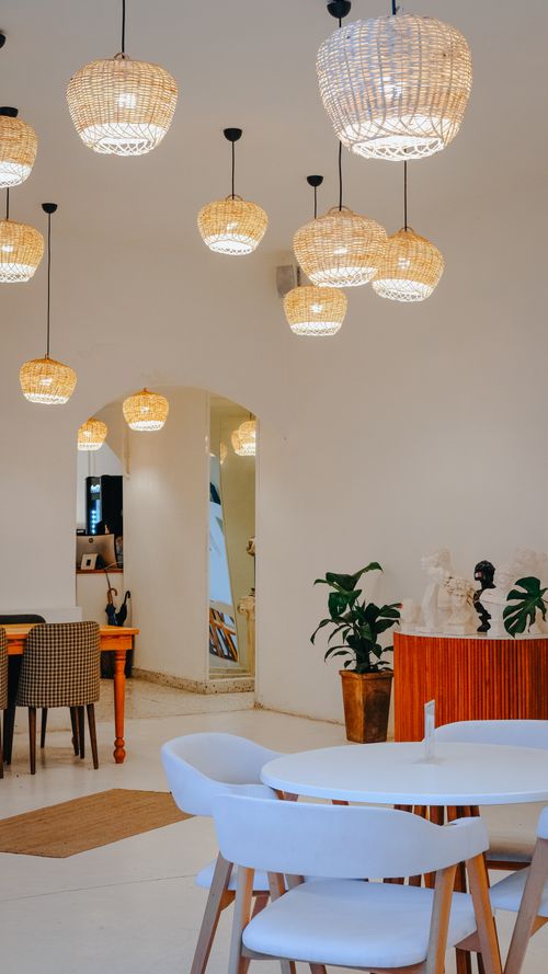 Free Stylish dining area featuring wicker pendant lights and modern furniture design. Stock Photo