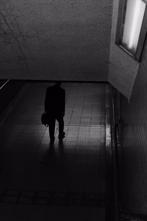 Free A monochrome silhouette of a person walking through an urban underpass. Stock Photo
