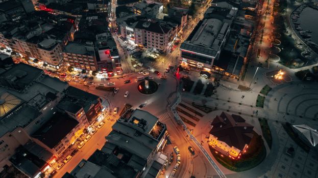 Aerial view of a vibrant city roundabout illuminated at night with traffic and bright lights.