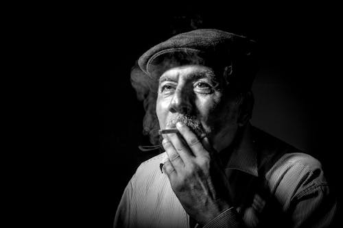 Grayscale Photo of an Elderly Man Smoking 