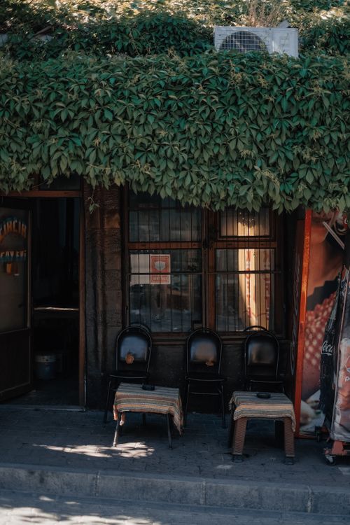 Free Charming outdoor cafe setting with ivy-covered facade and cozy seating. Stock Photo