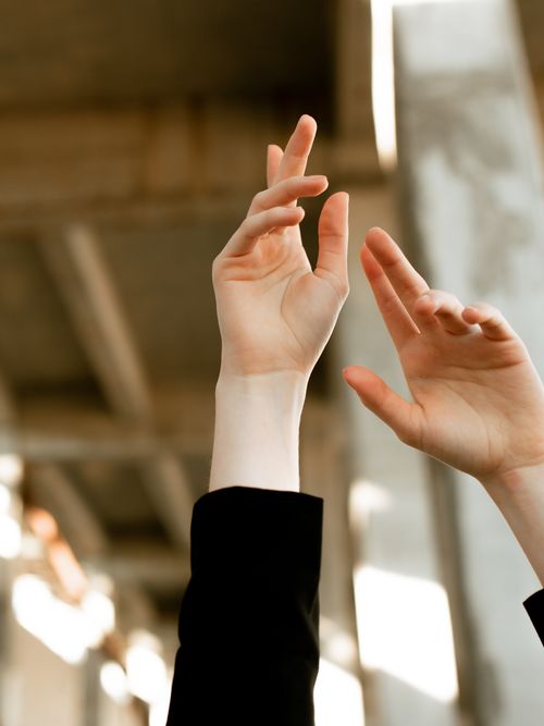 Free Close-up of hands reaching skyward under an urban bridge, expressing freedom and creativity. Stock Photo