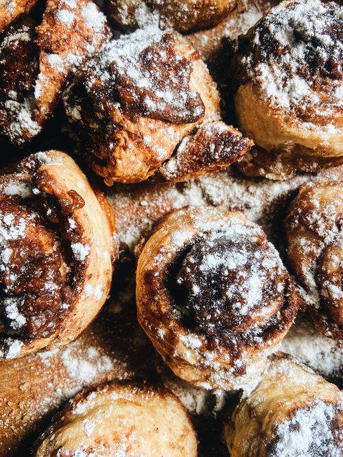 Free Delicious homemade cinnamon rolls dusted with powdered sugar. Perfect close-up shot for food lovers. Stock Photo