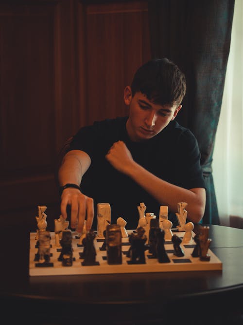 Free Man in Black Crew Neck T-shirt Playing Chess Stock Photo