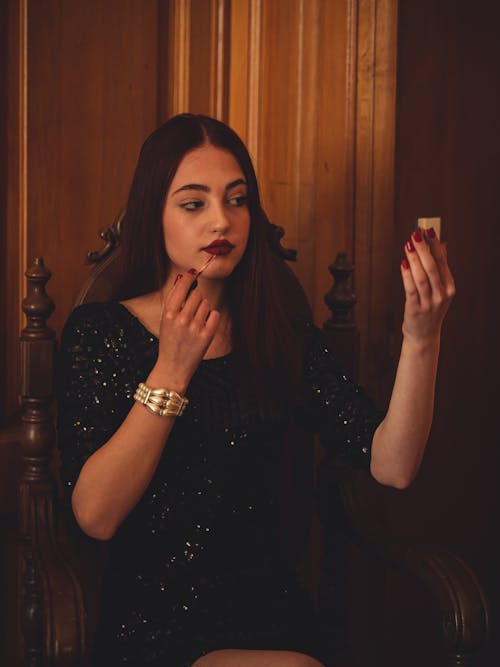 Woman in Black Dress Applying Lipstick