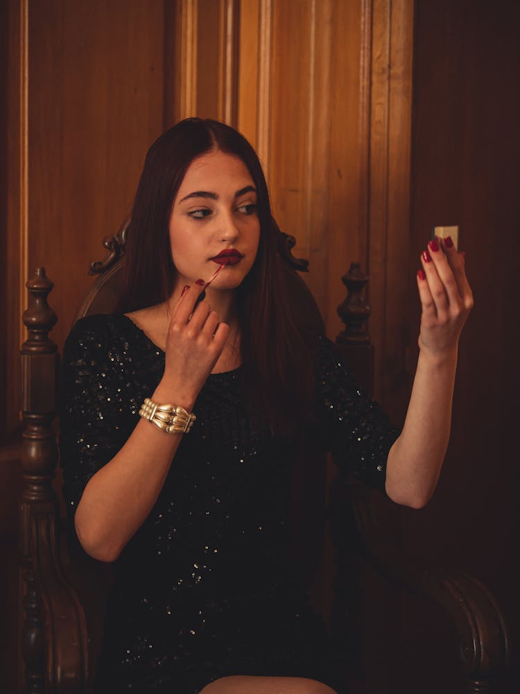 Woman In Black Dress Applying Lipstick