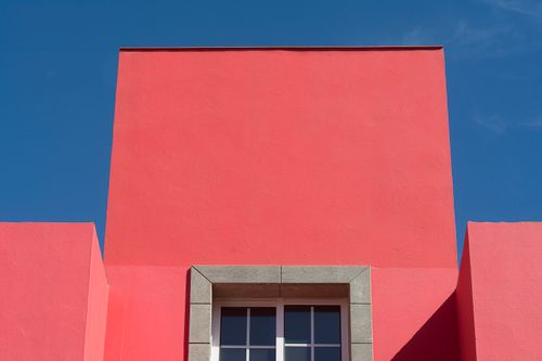 Free Vibrant red building facade against a clear blue sky beautifully captured. Stock Photo