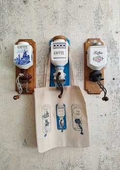 Vintage coffee grinders displayed on a retro wall with a themed tote bag.
