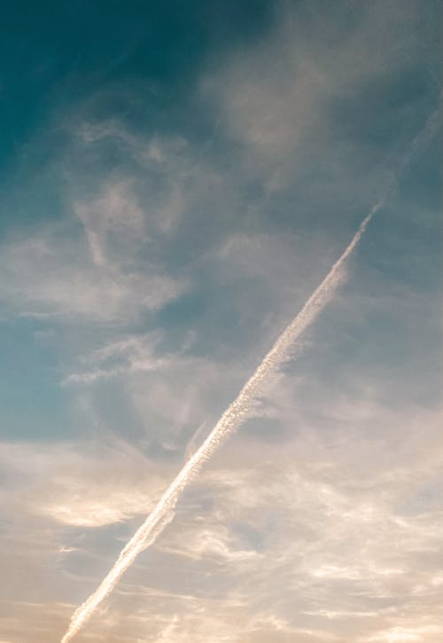 A Contrail on a Blue Sky With White Clouds