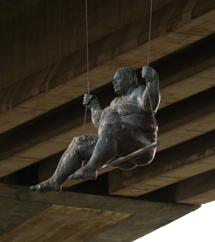 Stone Statue On Swing Hanging From Bridges Underside