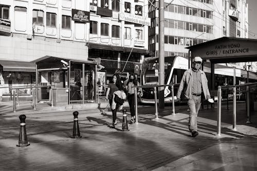 A Grayscale of People Walking on a Sidewalk