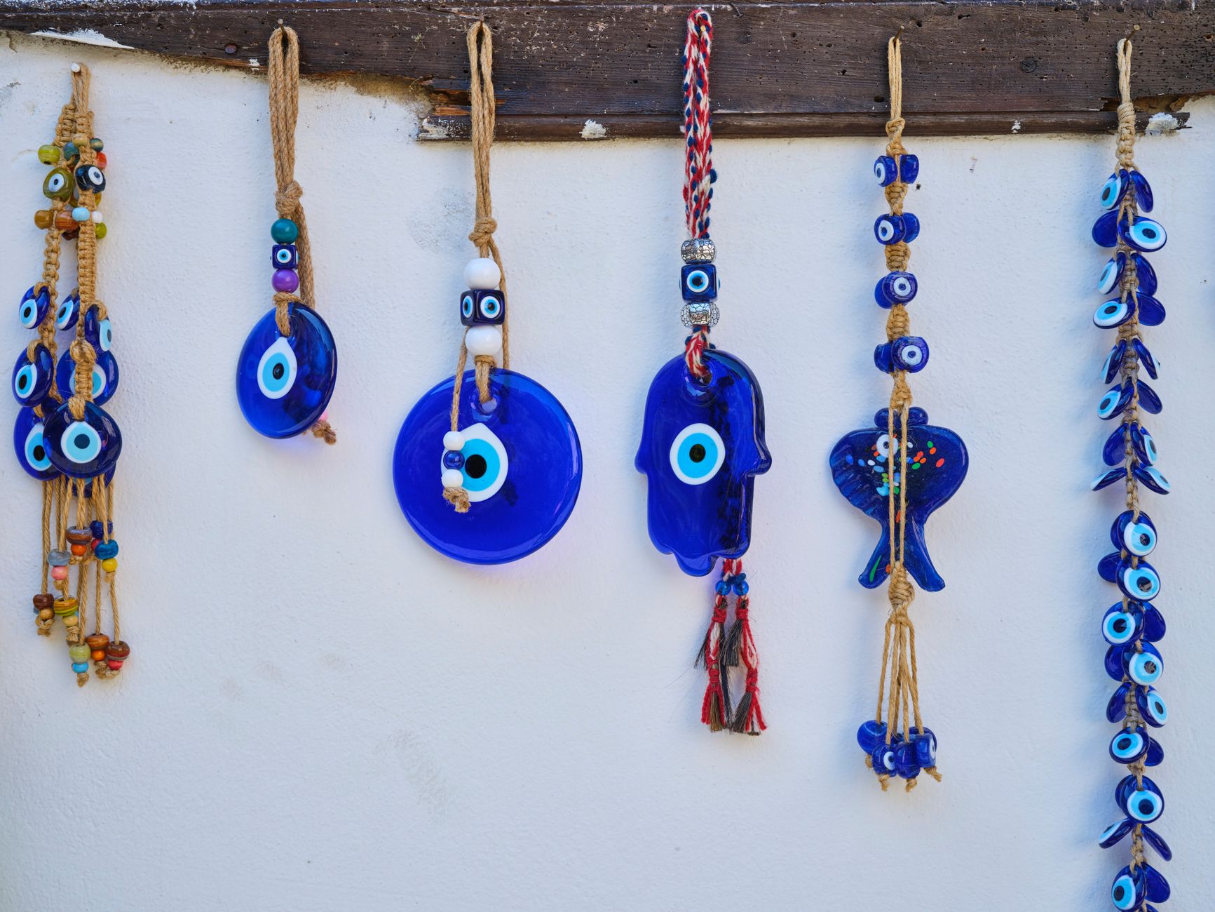 Colorful handmade evil eye wall decorations hanging on a white wall.