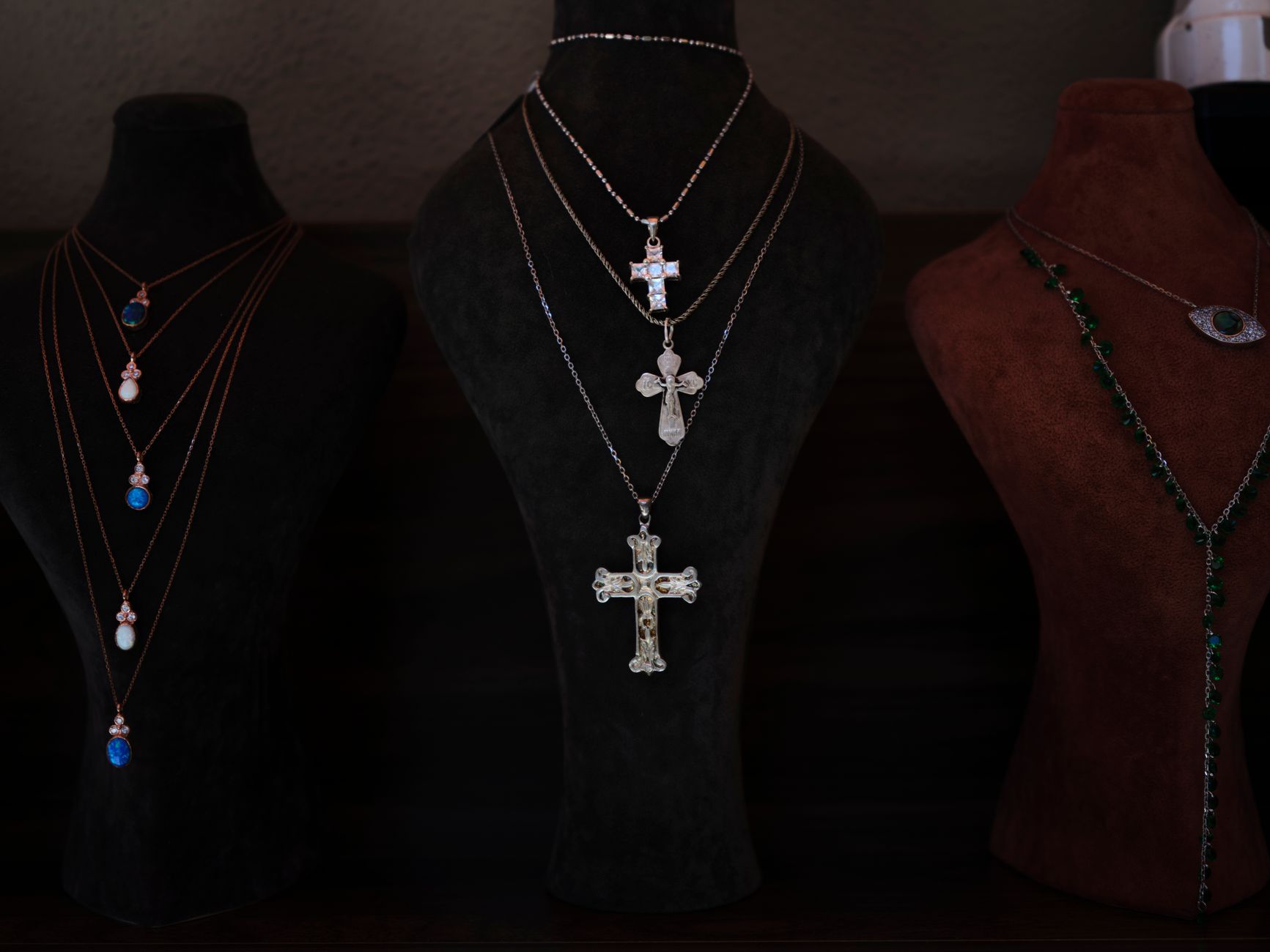 Showcase of elegant cross necklaces on velvet display busts. Perfect for religious and jewelry themes.