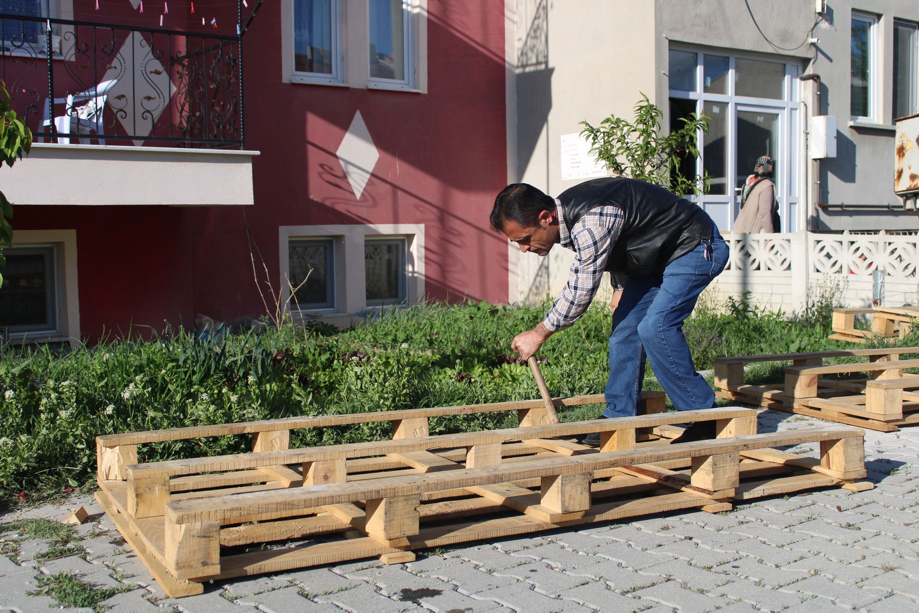 DIY Pallet Projects Using Materials from Home Depot Man assembling wooden pallet outside a building on a sunny day