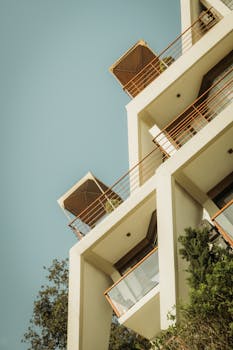 Low angle view of a modern residential building with balconies against the clear blue sky.