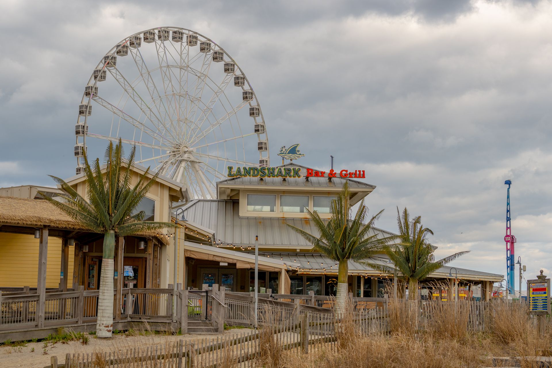 A cloudy day at an amusement park featuring a Ferris wheel and a bar & grill.