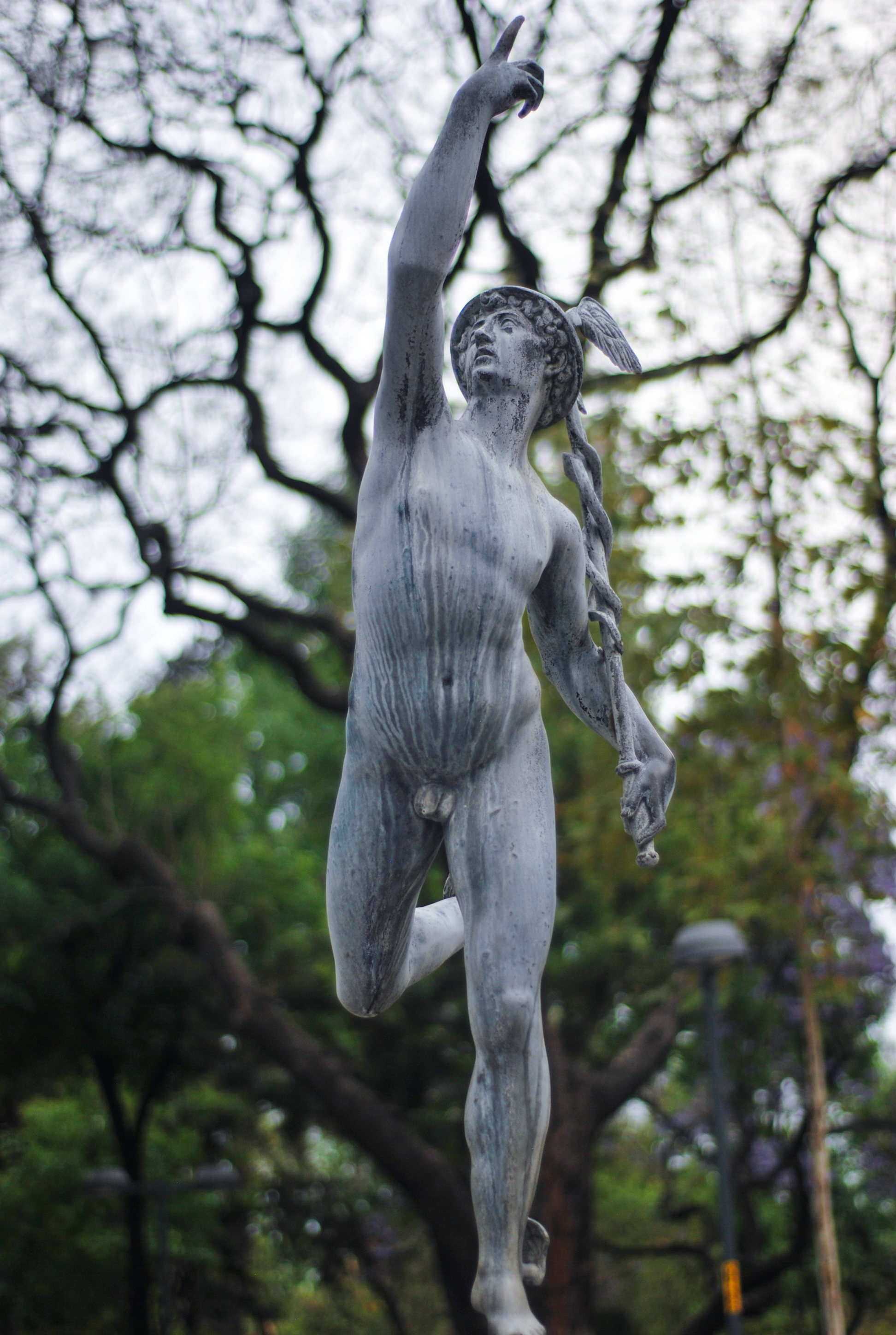 Elegant statue of Mercury with foliage backdrop, showcasing ancient artistry.