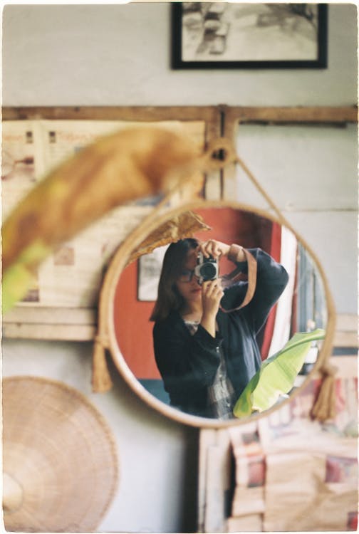 Mirror Reflection of a Woman Holding a Camera  