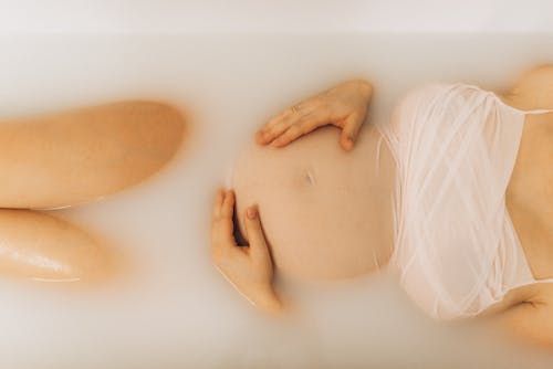 Free Unrecognizable Pregnant Woman Lying in Soapy Water in Bathtub Stock Photo
