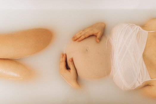 Unrecognizable Pregnant Woman Lying in Soapy Water in Bathtub