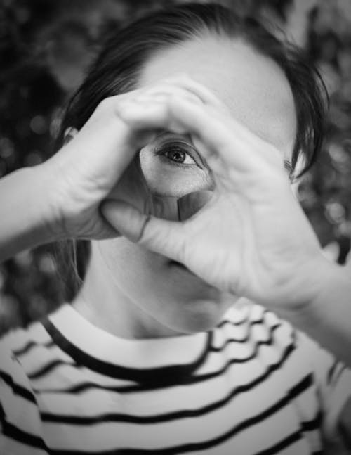 Grayscale Photo of Woman in Stripe Shirt Covering her Face with Hands