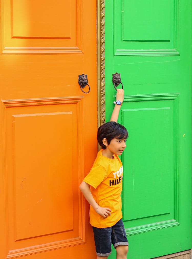 Boy Standing By Green And Orange Door