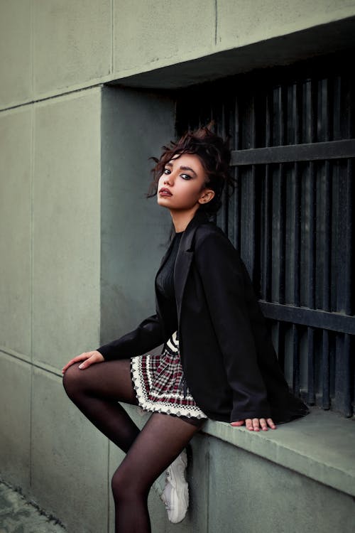 Woman in Black Jacket Sitting Beside a Window