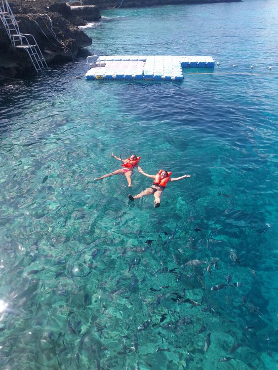 Frauen schwimmen mit Auftriebswesten im türkisfarbenen Meer
