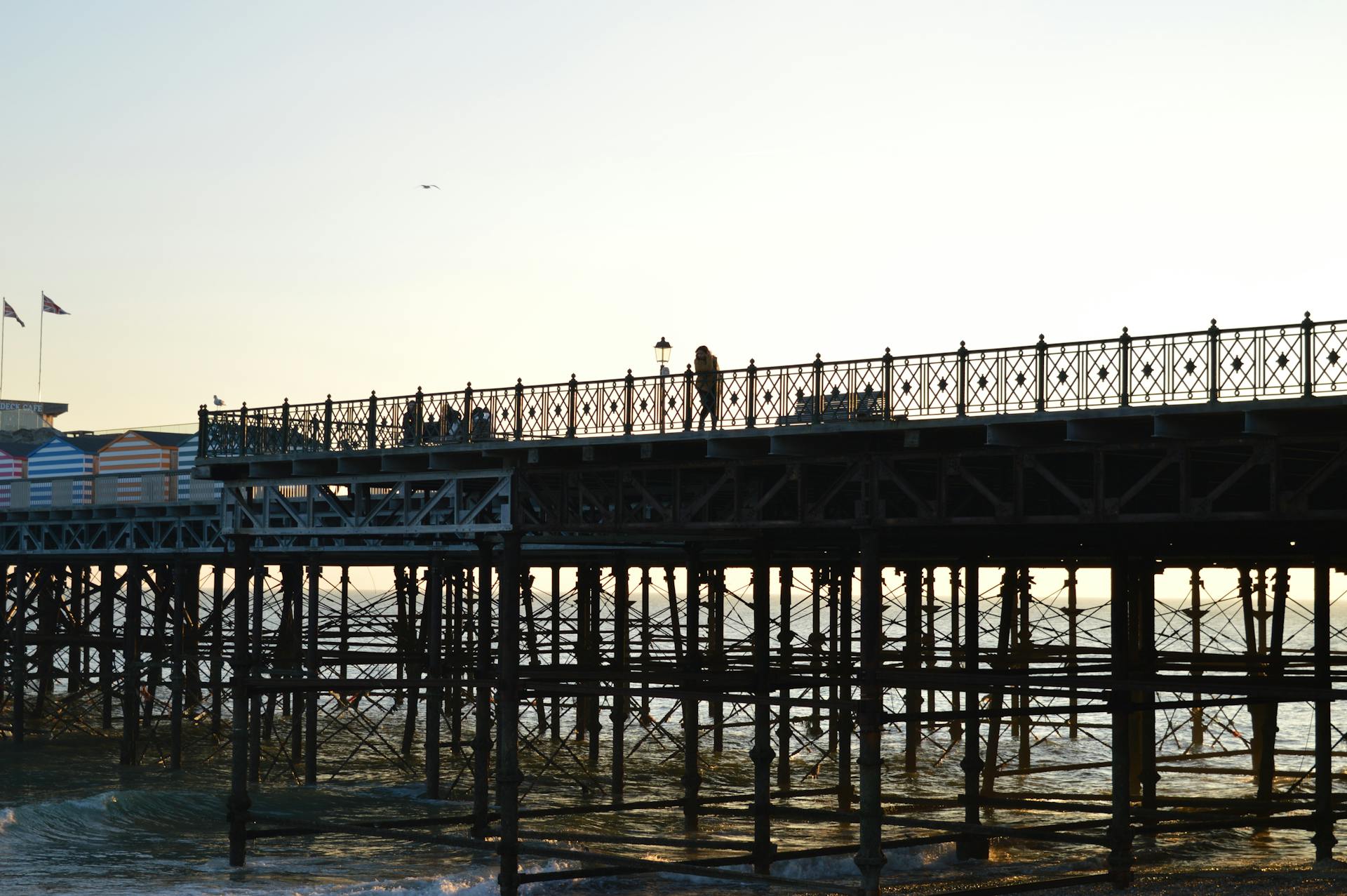 Silhouetted view of Hastings Pier and people walking at sunset.