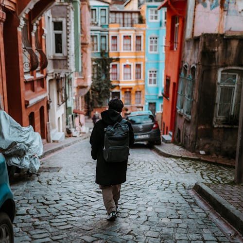 Man in Black Jacket Walking on Sidewalk