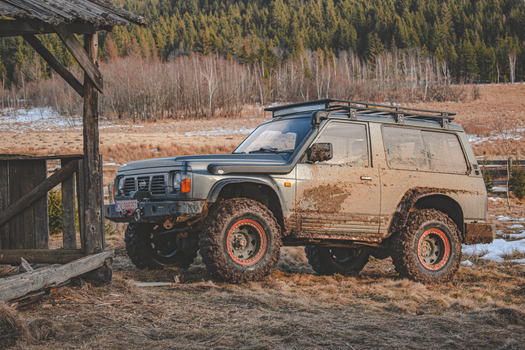 4x4 SUV parked on a muddy trail in Covasna, Romania, amidst a scenic wooded landscape. 12138612