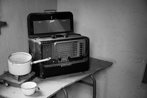 無料 調理鍋付きストーブの横にあるビンテージラジオのグレースケール写真 写真素材