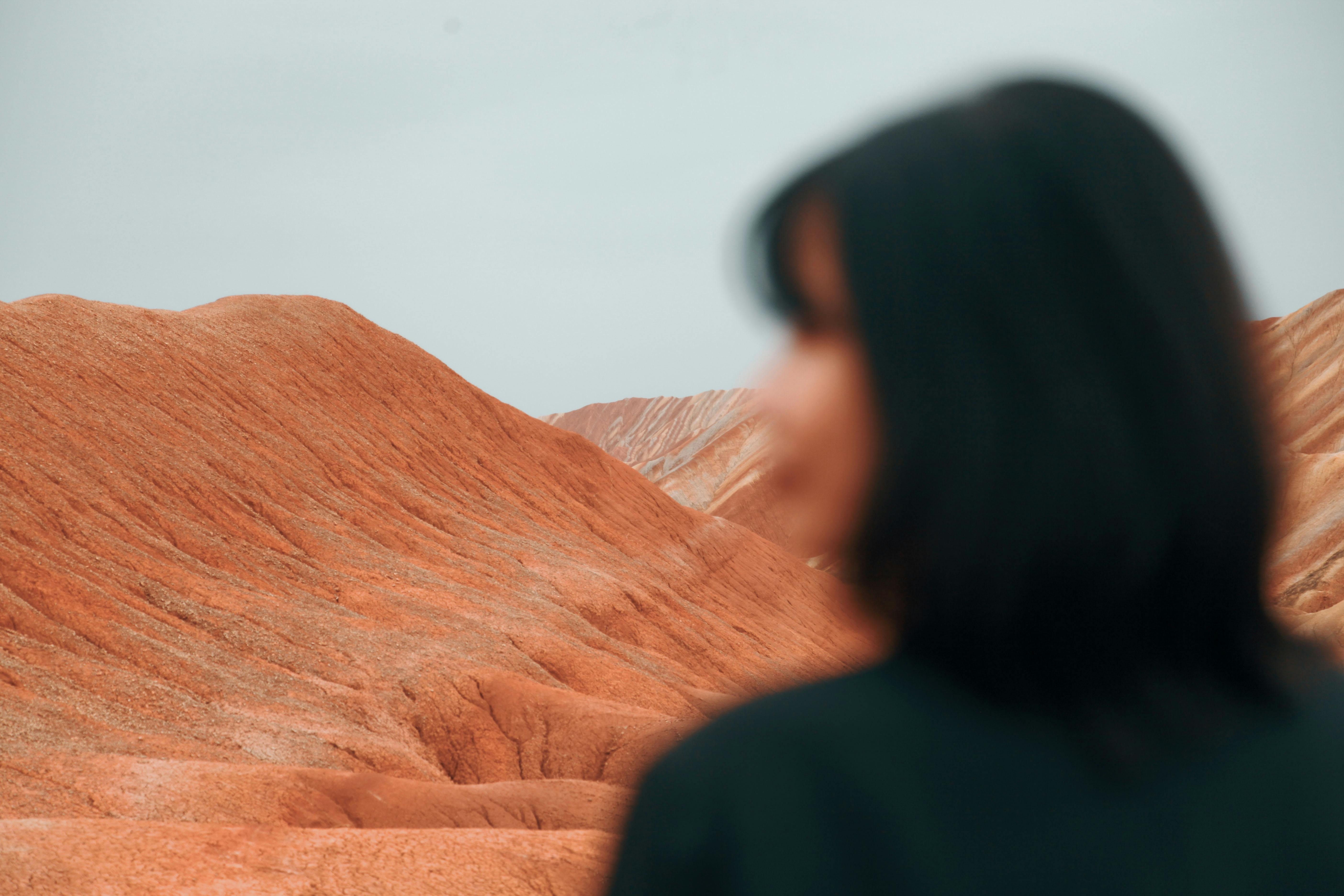 Woman gazing at the stunning Zhangye Danxia Geopark rock formations in China.