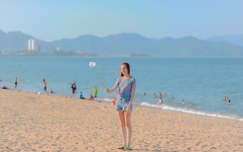 女人站在海边采取自拍照在白天使用独脚架