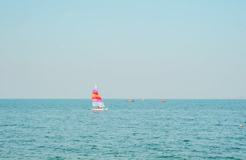 青い海の水に白とピンクのヨット