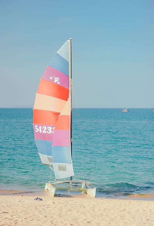 Multicolored Sail Boat on Shore Overlooking Sea Under Daytime Sky