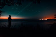 黄昏时分，星空下海边一个人拿着手电筒的剪影